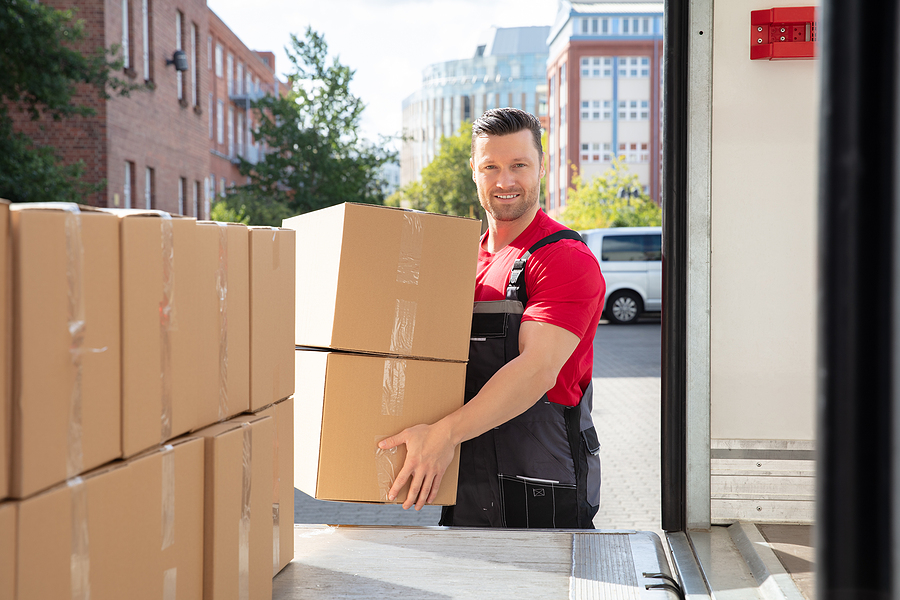 Smiling removalist loading a box to a van